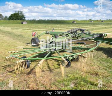 tracteur dans le champ avec faneuse d'herbe pendant la récolte du foin aux pays-bas sous ciel bleu Banque D'Images