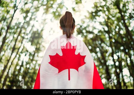 Enfant adolescente fille dans la nature fond un drapeau du Canada sur ses épaules Banque D'Images