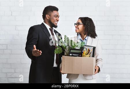 Jeune femme souriante avec boîte de choses personnelles étant embauchées pour travailler en entreprise, rencontrer son nouveau patron Banque D'Images