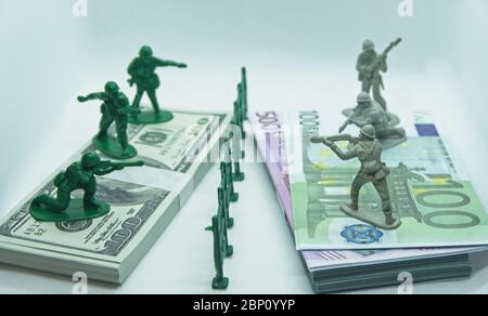 Miniature en plastique figure de soldats sur deux paquets, l'un fait de billets de dollars et l'autre d'euros avec un fossé en plastique au milieu Banque D'Images