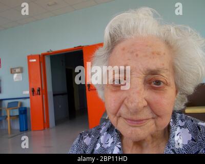 Une vieille dame charmante souriant et regardant l'appareil photo. Banque D'Images