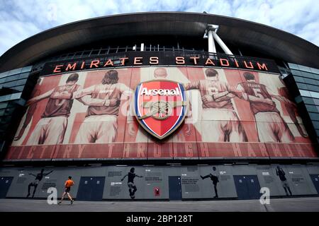 Un jogger solitaire passe devant le stade Emirates, qui abrite Arsenal, aurait dû voir Arsenal prendre Watford dans ce qui aurait été leur dernier match de la Premier League de la saison 19/20. Banque D'Images