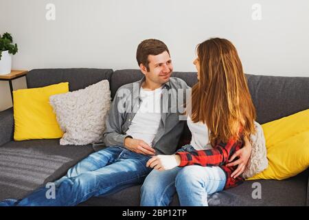 Un jeune couple souriant sur un canapé Banque D'Images