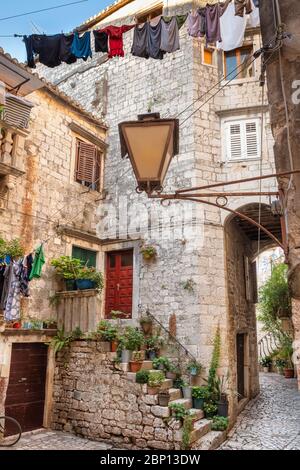 Rue pittoresque et étroite de la ville de Trogir avec pots de fleurs et sèche linge Banque D'Images