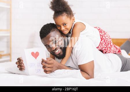 Petite fille félicitant son papa avec la fête des pères avec carte de salutation Banque D'Images