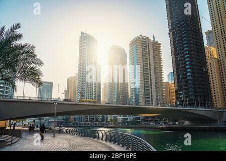 Dubai Marina promenade avec chemin de promenade, canal avec bateaux et bâtiments élevés au soleil, Émirats arabes Unis, Moyen-Orient. Banque D'Images