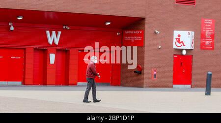 Un homme portant un masque (couvrant) passe devant Anfield - Maison des surmontoirs de table de Premiership Liverpool. Aujourd'hui, Liverpool aurait dû jouer leur dernier match des 19/20 loin à Newcastle au parc St James. Banque D'Images