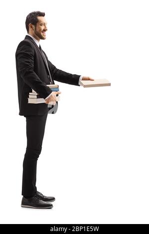 Photo de profil complet d'un homme en costume noir donnant un livre et souriant isolé sur fond blanc Banque D'Images