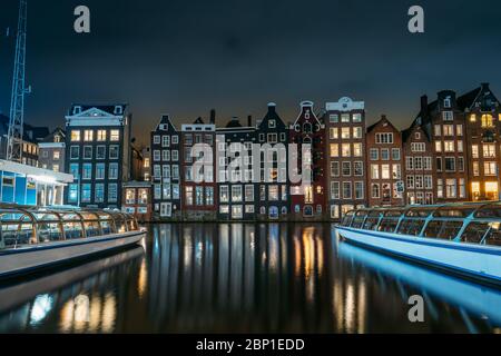 Amsterdam canal Singel avec maisons dansantes et bateaux à moteur la nuit avec réflexion de l'éclairage dans l'eau, pays-Bas. Banque D'Images