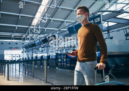 Homme portant un masque et marchant dans le terminal de l'aéroport. Thèmes voyageant pendant une pandémie et protection personnelle. Banque D'Images