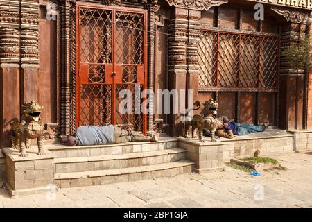 Katmandou, Népal - 25 novembre 2016 : deux hommes népalais adultes dorment sur les marches devant l'entrée du temple. Banque D'Images