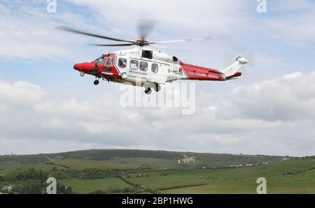 Un hélicoptère AW189 AgustaWestland de HM Coastguard arrive à terre sur le côté de la falaise près de Overcombe à Dorset, pendant un exercice d'entraînement. Banque D'Images