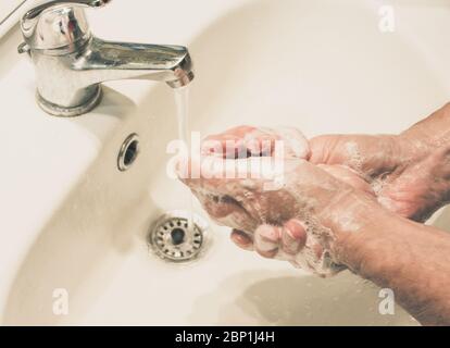 l'homme mûr se lave les mains avec de l'eau courante et du savon. Protection contre les infections.se laver les mains contre le virus Banque D'Images