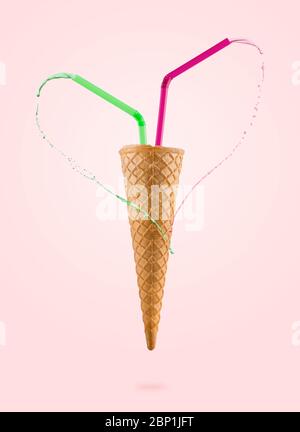videz les cônes de glace avec des pailles colorées et du lait égoutté, sur fond coloré Banque D'Images
