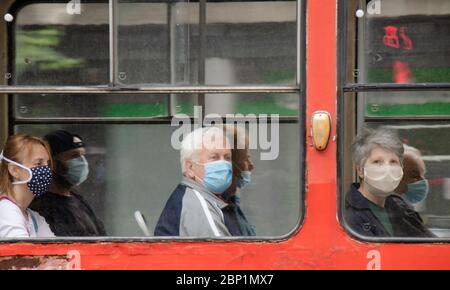 Belgrade, Serbie - 15 mai 2020 : personnes portant un masque chirurgical tout en étant assis et en conduisant dans un siège de fenêtre d'un tramway, de l'extérieur Banque D'Images