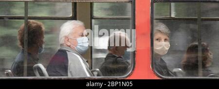 Belgrade, Serbie - 15 mai 2020 : personnes portant un masque chirurgical tout en étant assis et en conduisant dans un siège de fenêtre d'un tramway, de l'extérieur Banque D'Images