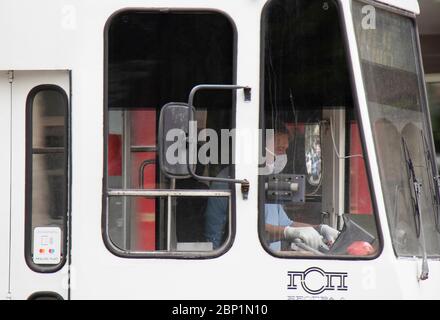 Belgrade, Serbie - 15 mai 2020 : conducteur de tramway portant des masques et des gants chirurgicaux tout en conduisant un tramway blanc, de l'extérieur Banque D'Images