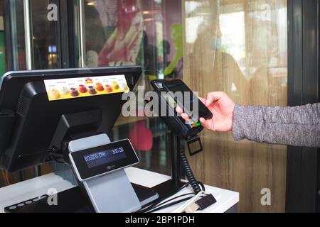 Lviv, Ukraine - 17 mai 2020 : restaurant McDonalds, le client paie avec son smartphone en utilisant la technologie NFC sans aucun contrôle. Sans contact et social dis Banque D'Images