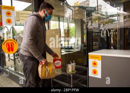 Lviv, Ukraine - 17 mai 2020 : restaurant McDonalds, homme prenant sa commande sans aucun effort. Concept de soins de santé et de distance sociale, réouverture Banque D'Images