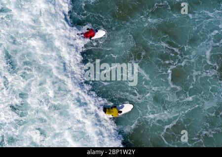 Photo aérienne des surfeurs essayant de prendre une vague dans l'océan Banque D'Images