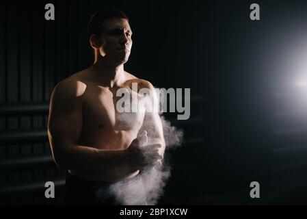 Haltérophilie claquant les mains avec le talc avant de lever la barbell à la salle de gym. Banque D'Images