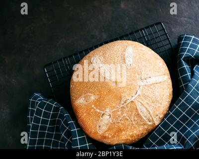 Pain de levain rond de blé. Vue de dessus de délicieux pain de levain maison sur fond noir avec espace de copie. Concept de fabrication de pain au levain fait maison. Banque D'Images