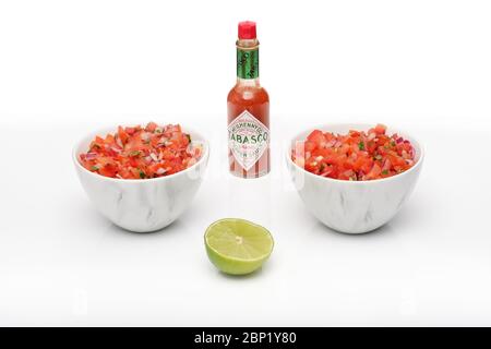 2 bols identiques contenant de la salsa fraîchement préparée avec une bouteille de sauce tabasco Banque D'Images