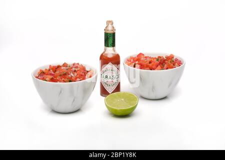 2 bols identiques contenant de la salsa fraîchement préparée avec une bouteille de sauce tabasco et une demi-tranche de lime fraîche Banque D'Images