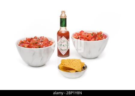 2 bols identiques contenant de la salsa fraîchement préparée avec une bouteille de sauce tabasco et un bol de chips tortilla Banque D'Images