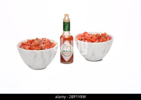 2 bols identiques contenant de la salsa fraîchement préparée avec une bouteille de sauce tabasco Banque D'Images