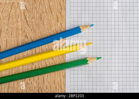 trois crayons de couleur et un morceau de papier sur une table en bois Banque D'Images