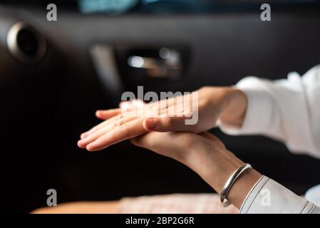 Femme utilisant un désinfectant pour les mains dans la voiture pour se désinfecter les mains à l'extérieur afin d'empêcher la propagation du virus pendant la pandémie Banque D'Images