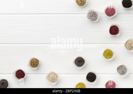 De nombreuses boules d'énergie végétaliennes colorées sur une table en bois blanc Banque D'Images