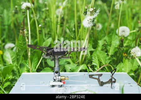 Brûleur à gaz touristique et buse interchangeable sur une table dans l'herbe, concept de confort de camping de randonnée. Banque D'Images