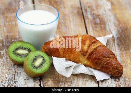 Petit déjeuner simple : croissant français, kiwi et verre de lait Banque D'Images