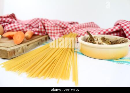 Produits alimentaires disposés sur la table à volants, avec des carrés rouges et blancs. Cuisine méditerranéenne italienne avec spaghetti et champignons porcini séchés. Banque D'Images
