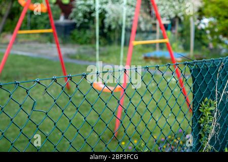 Balançoire pour enfants dans un jardin dans une clôture, Focus sur la clôture, extérieur Banque D'Images