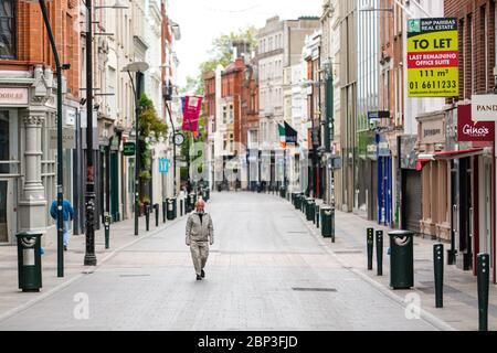 Homme de haut niveau qui marche dans la rue Grafton déserte du centre-ville de Dublin alors que la chute de pied s'effondre en raison de la pandémie du coronavirus. Covid-19 en Irlande. Banque D'Images