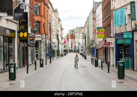 Homme de haut niveau qui marche dans la rue Grafton déserte du centre-ville de Dublin alors que la chute de pied s'effondre en raison de la pandémie du coronavirus. Covid-19 en Irlande. Banque D'Images