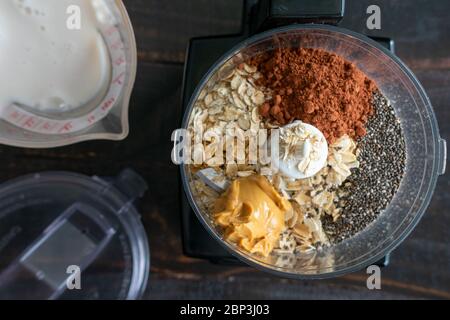 Chocolat pour la nuit avoine Smoothie Ingrédients: Flocons d'avoine, graines de chia, et autres ingrédients pour le smoothie de petit déjeuner dans un bol de robot ménager Banque D'Images