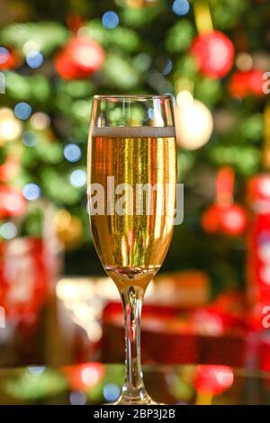 Flûte de champagne sur une table avec un arbre de Noël et présente floue en arrière-plan Banque D'Images