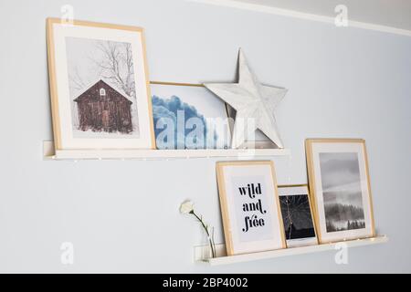 Étagères murales décorées avec une composition de gravures, une étoile en bois et des guirlandes lumineuses. Décoration maison. Banque D'Images