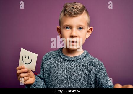 Jeune petit casien montrant un visage souriant sur une note papier comme message heureux agacé et frustré criant avec colère, fou et hurlant avec la rai Banque D'Images