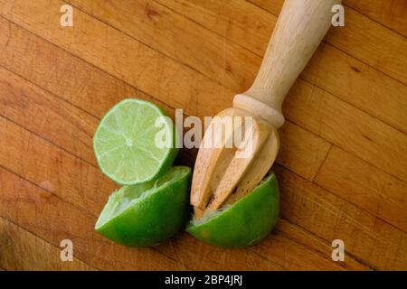 Limon juteux coupé en deux sur une planche à découper en bois avec un alésoir d'agrumes en bois; pressé ou alésé pour le jus. Banque D'Images