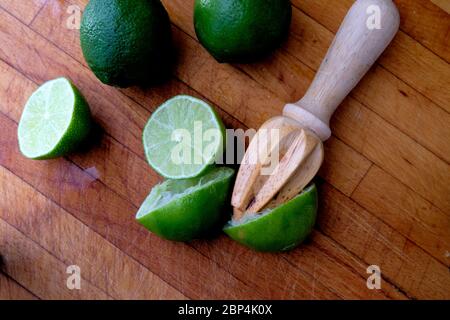 Limon juteux coupé en deux sur une planche à découper en bois avec un alésoir d'agrumes en bois; pressé ou alésé pour le jus. Banque D'Images