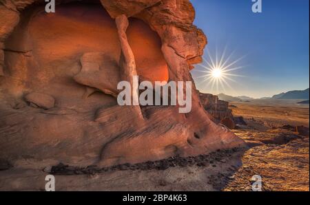 Un spectaculaire lever de soleil sur la falaise, tiré de Wadi Rum, en Jordanie, avec le désert au loin avec un sunstar et une grande formation de rochers illuminés le matin Banque D'Images