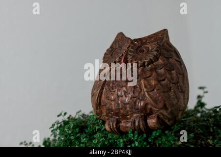 hibou en bois sculpté isolé du fond sur une couche de lierre Banque D'Images