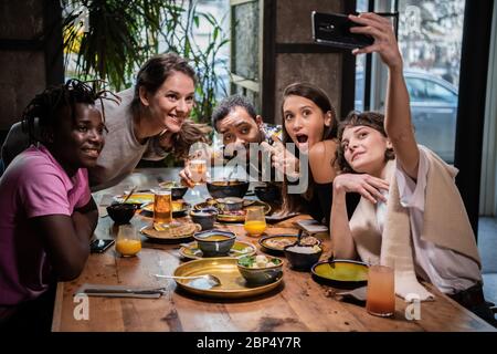 Groupe de jeunes étudiants faisant des visages drôles, prenant des selfies avec Banque D'Images