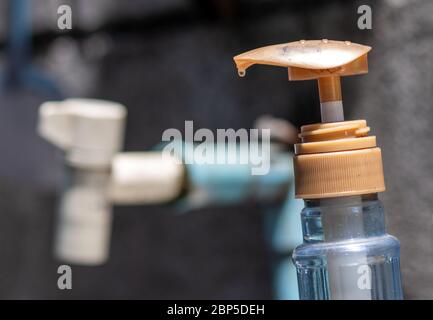 Un robinet et un détergent à vaisselle dans la cuisine extérieure. Un robinet en gros plan et une bouteille en plastique avec un liquide de désinfection ou du savon. Banque D'Images