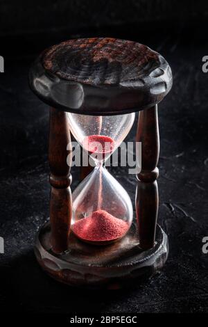 Le temps est écoulé. Un sablier avec du sable tombant à travers, sur un fond noir Banque D'Images